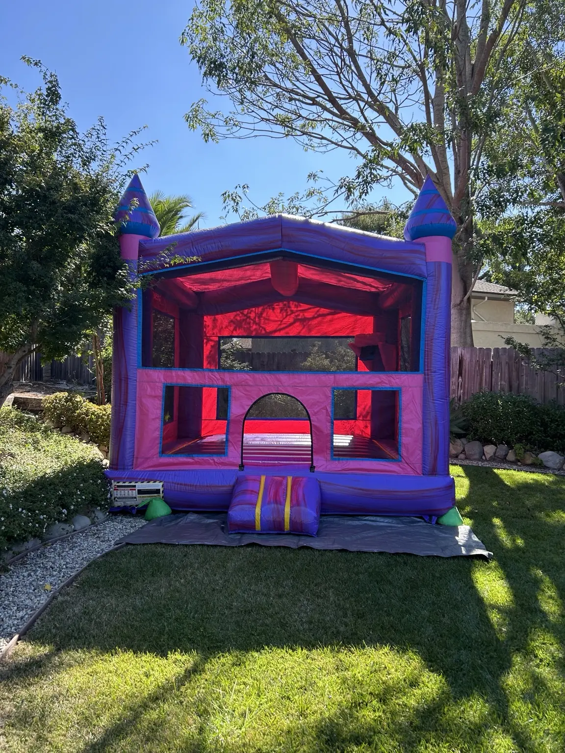 Pink and purple bounce house set up in a backyard