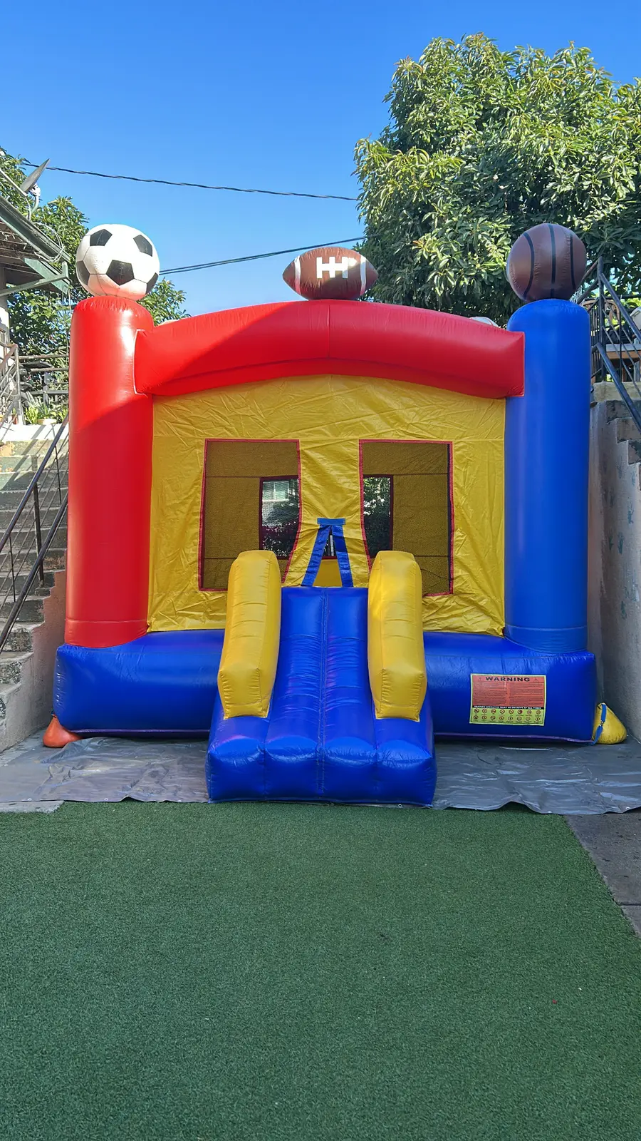 Colorful sports-themed bounce house with a front entrance